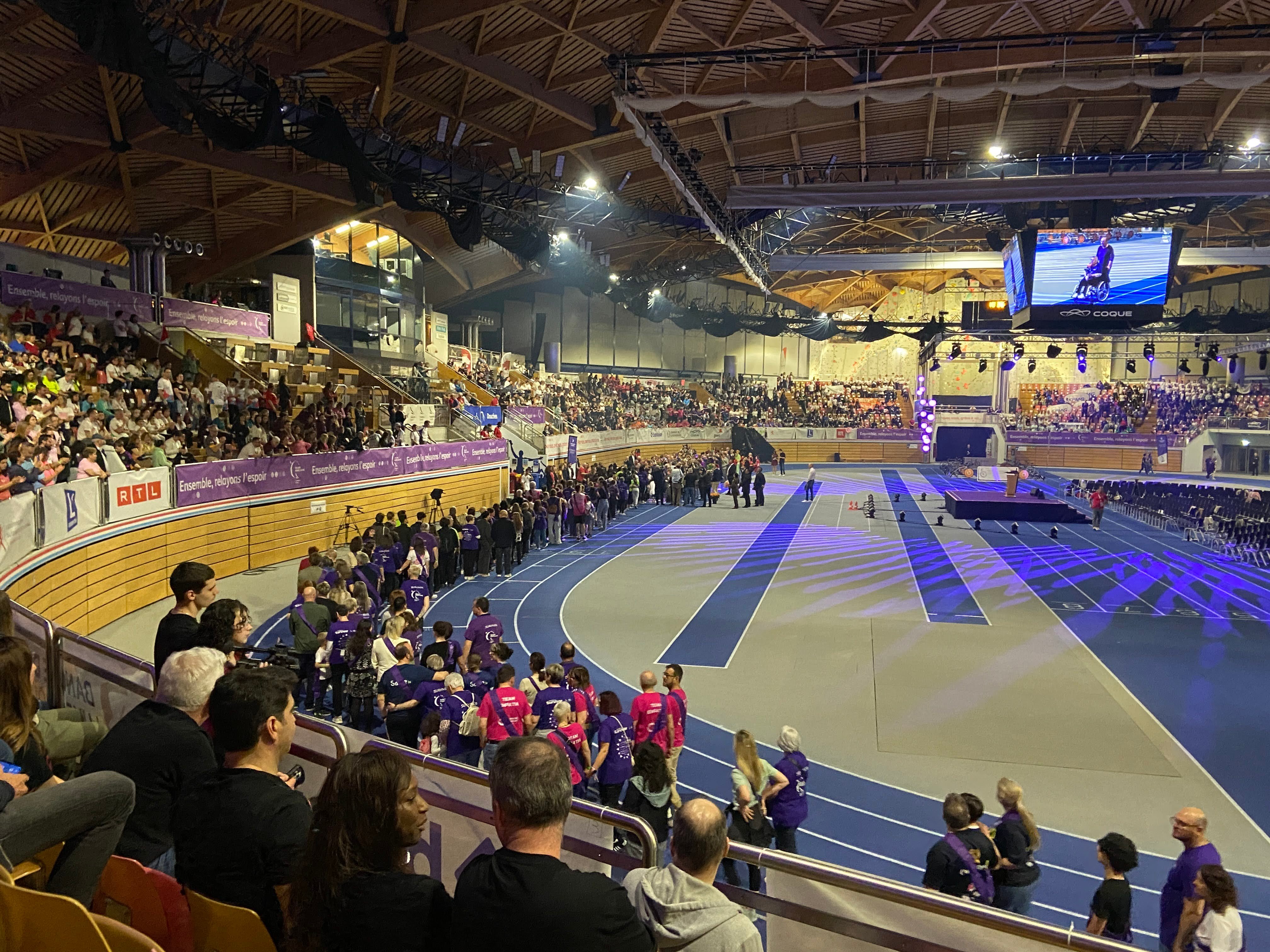 Hundreds of people walking on indoor athletics track